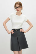 Woman wearing a white top and black skirt with a plain background
