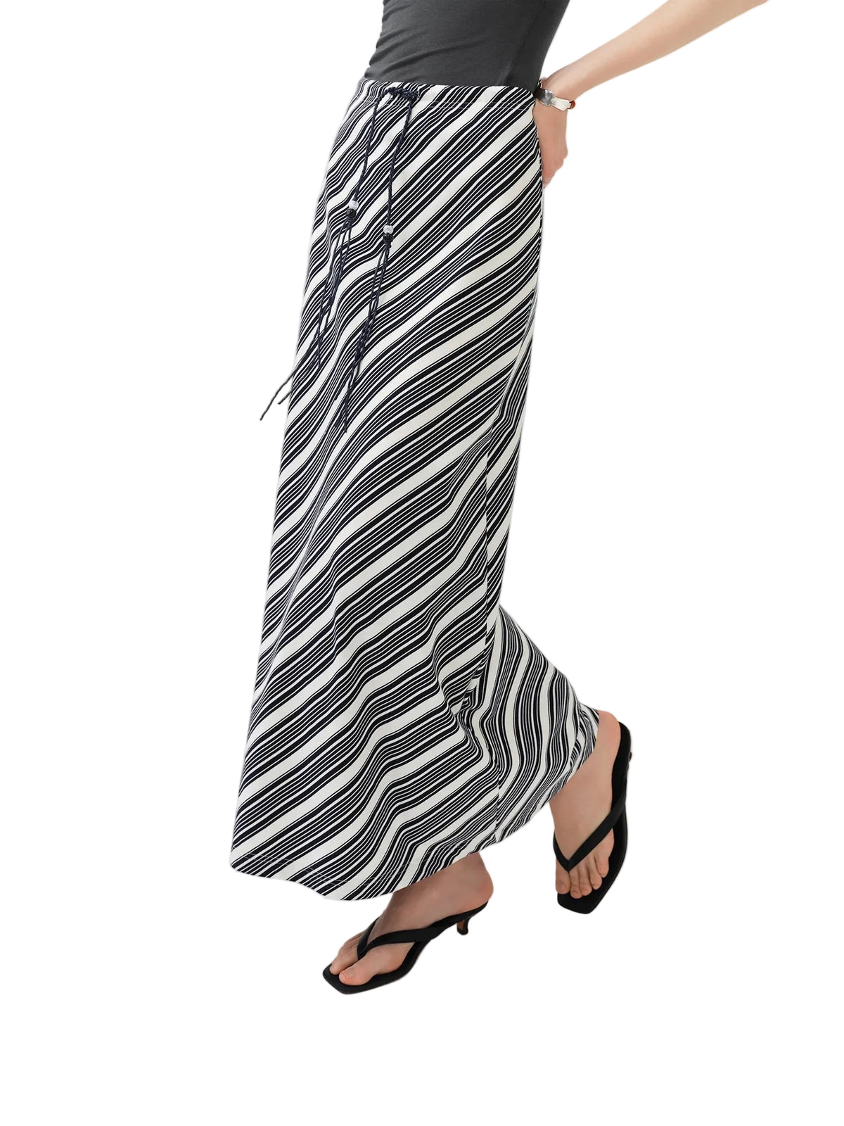 A model wearing a pair of wide-leg, black and white striped maxi skirt with a drawstring waist, styled with a black top and black thong sandals. The brand logo 'fsle' is visible in the top left corner.