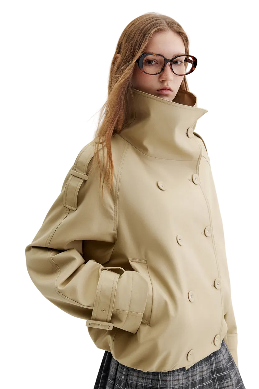 A model wearing a beige double-breasted trench jacket with a high collar and large buttons, paired with a plaid skirt. The brand logo 'fsle' is visible in the top left corner.