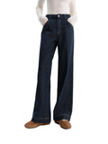 Person wearing dark blue wide-leg jeans on a white background with 'fsle' branding.